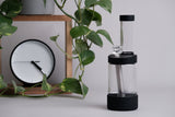a glass vase with a diamond in it next to a clock