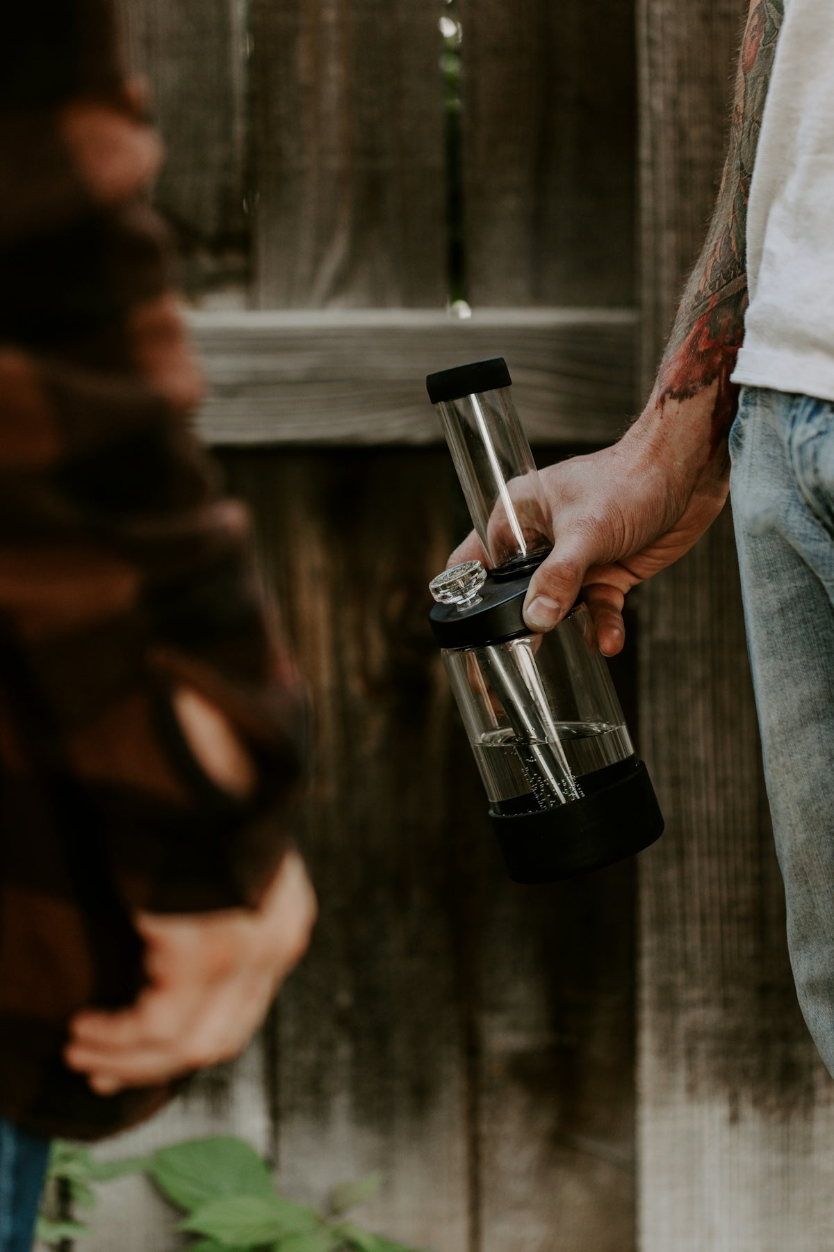a man is holding a glass container with a cigarette in it